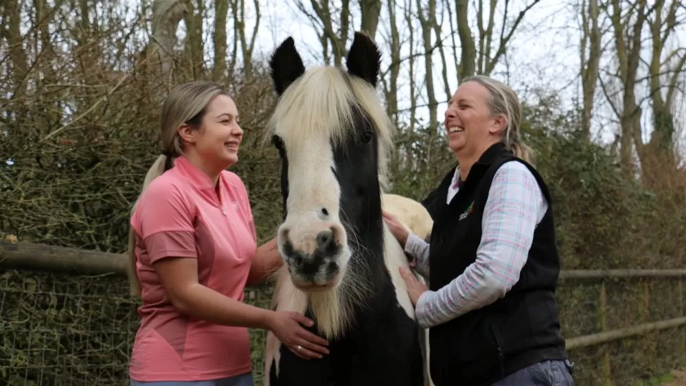 Audrey, a black and white pony, stands between her new Guardian on the left and Redwings Nursing Manager Lou on the right.