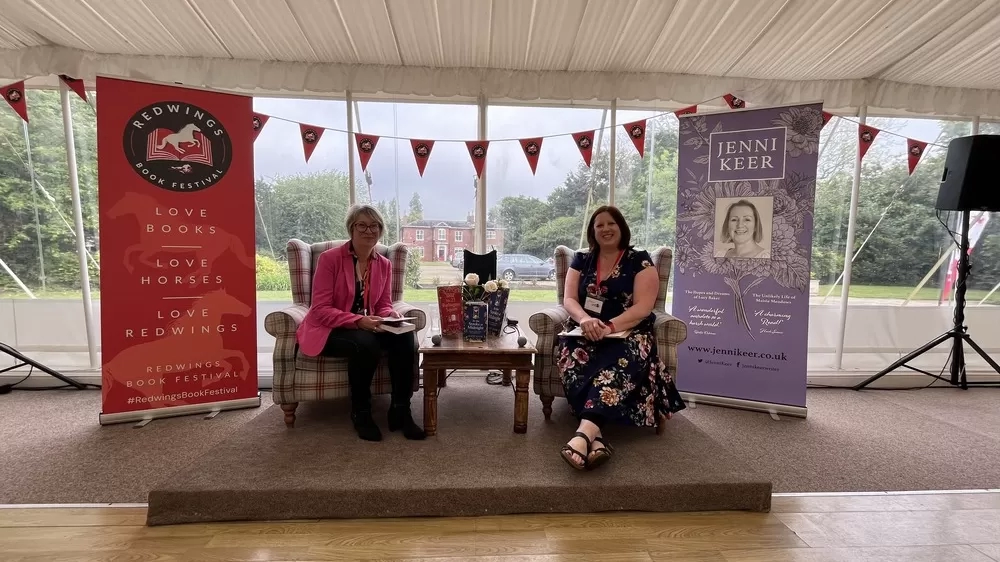 Two women sits on armchairs in a marquee hosting the Redwings Book Festival.