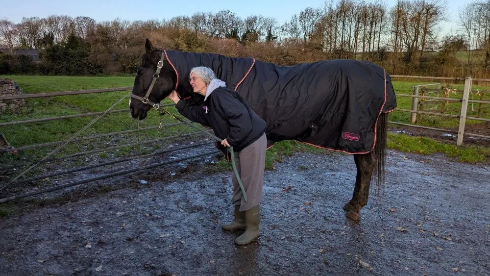 Lucy the horse stood wearing a rug beside her owner.