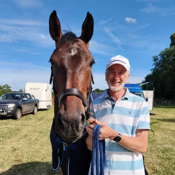 Ian, a Redwings trustee, is stood next to a large horse - they are both looking at the camera