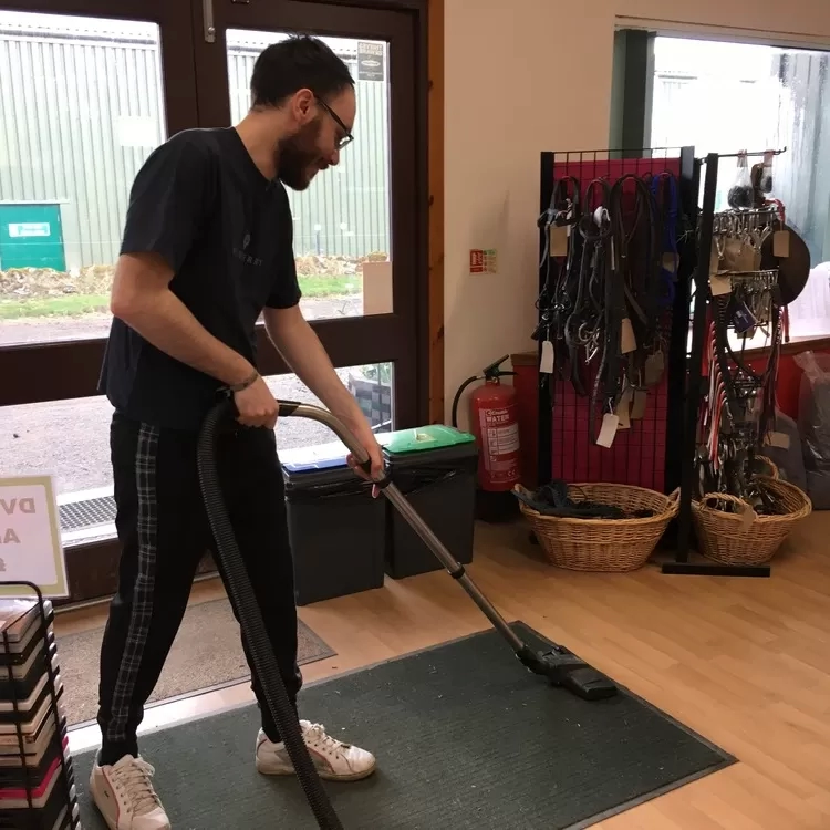 A man is hoovering a mat inside one of the Redwings visitor centres 