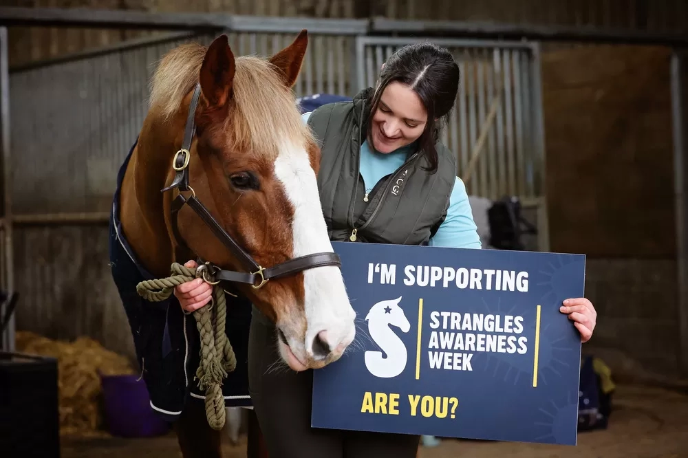 Rhi holding a SAW ambassador sign next to her horse Harley