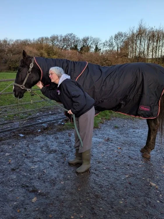 Lucy the horse stood wearing a rug beside her owner.