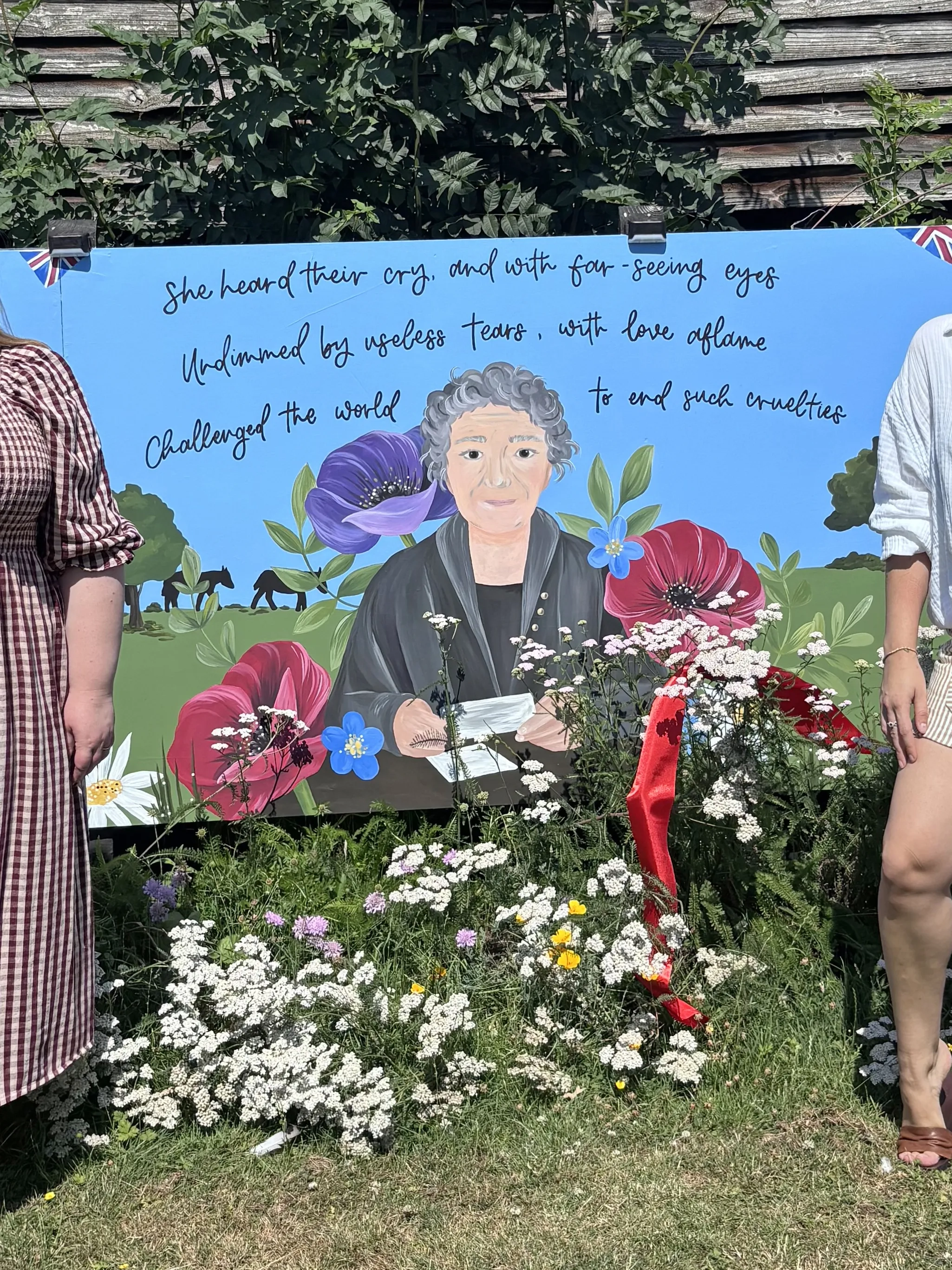 Photo of Stacey the artist and Olivia Bowen stood in front of the new mural at Redwings Ada Cole. 